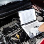 Mechanik kontroluje motor auta počas pravidelného servisu v autoservise.