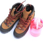 Zablatené turistické topánky položené na kameni po náročnej túre v horách.