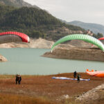 Začiatočník pripravujúci sa na paragliding s inštruktorom na štartovacej lúke.