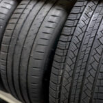 Dve autá pri teste núdzového brzdenia na mokrej vozovke, ilustrujúce rozdiel v brzdnej dráhe medzi úzkymi a širokými pneumatikami.